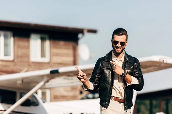 Happy Stylish Man Leather Jacket Sunglasses Pointing Fingers Airplane — Stock Photo, Image