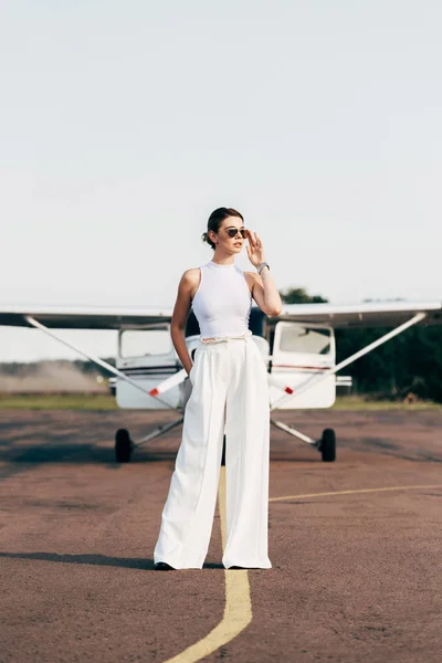 Çekici Şık Genç Kadın Uzağa Bakarak Uçak Poz Güneş Gözlüğü — Stok fotoğraf
