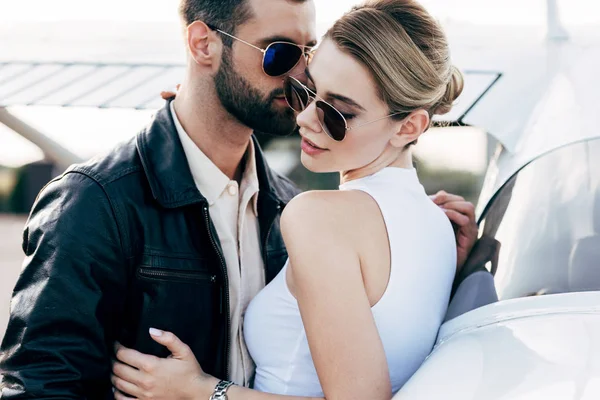 Homem Elegante Jaqueta Couro Óculos Sol Abraçando Namorada Atraente Perto — Fotografia de Stock