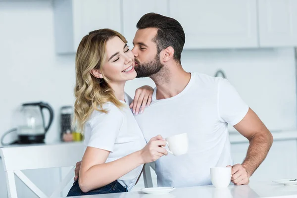 Bonito Barbudo Homem Beijos Sorrindo Namorada Enquanto Bebendo Café Juntos — Fotografia de Stock