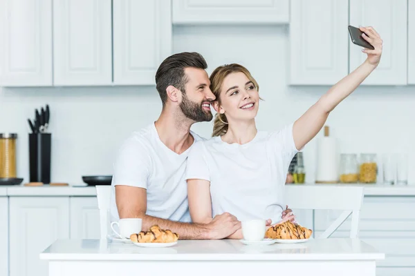 快乐的年轻夫妇采取自拍与智能手机在一起吃早餐 — 图库照片