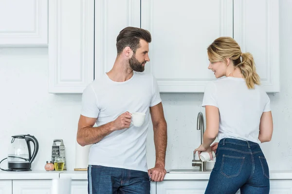 Schöner Junger Mann Schaut Freundin Beim Kaffeetassenwaschen Küche — Stockfoto