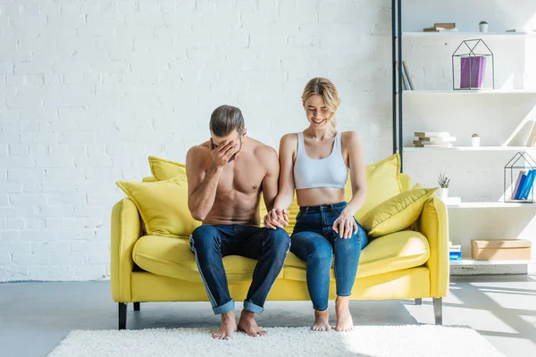 Feliz Jovem Casal Mãos Dadas Rindo Enquanto Sentados Juntos Sofá — Fotografia de Stock