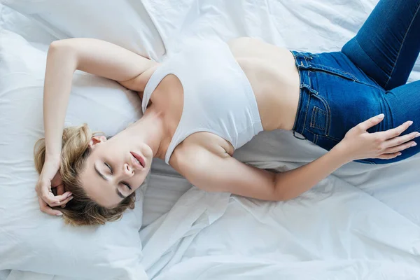 ベッドで眠っている美しい若い女性のトップ ビュー  — 無料ストックフォト