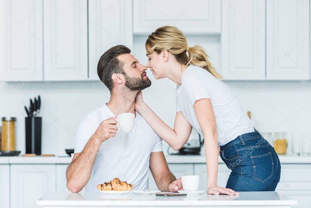 beautiful young couple in love able to kiss while having breakfast together