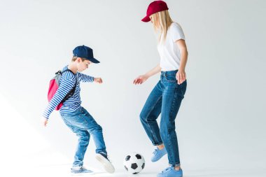 Anne ve oğlu futbol oynarken üzerine beyaz sırt çantası ile yan görünüm