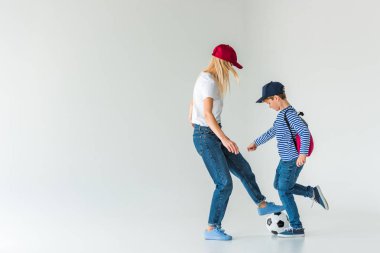 Anne ve oğlu futbol oynarken üzerine beyaz sırt çantası ile yan görünüm