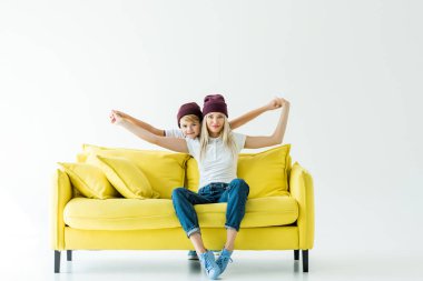 Anne ve oğlu sarı beyaz koltukta üzerinde uçan gibi davranarak Bordo şapka içinde