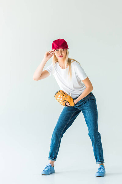 beautiful baseball player touching red cap and holding baseball glove isolated on white
