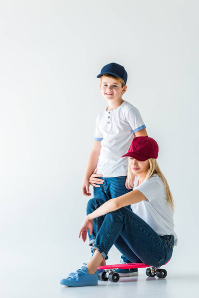 mother sitting on skate and hugging son on white