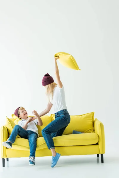 Mutter Hat Spaß Und Schlägt Sohn Mit Kopfkissen Auf Gelbem — kostenloses Stockfoto