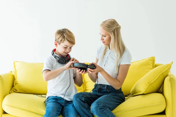 Madre Hijo Sosteniendo Auriculares Sofá Amarillo Aislado Blanco — Foto de stock gratis