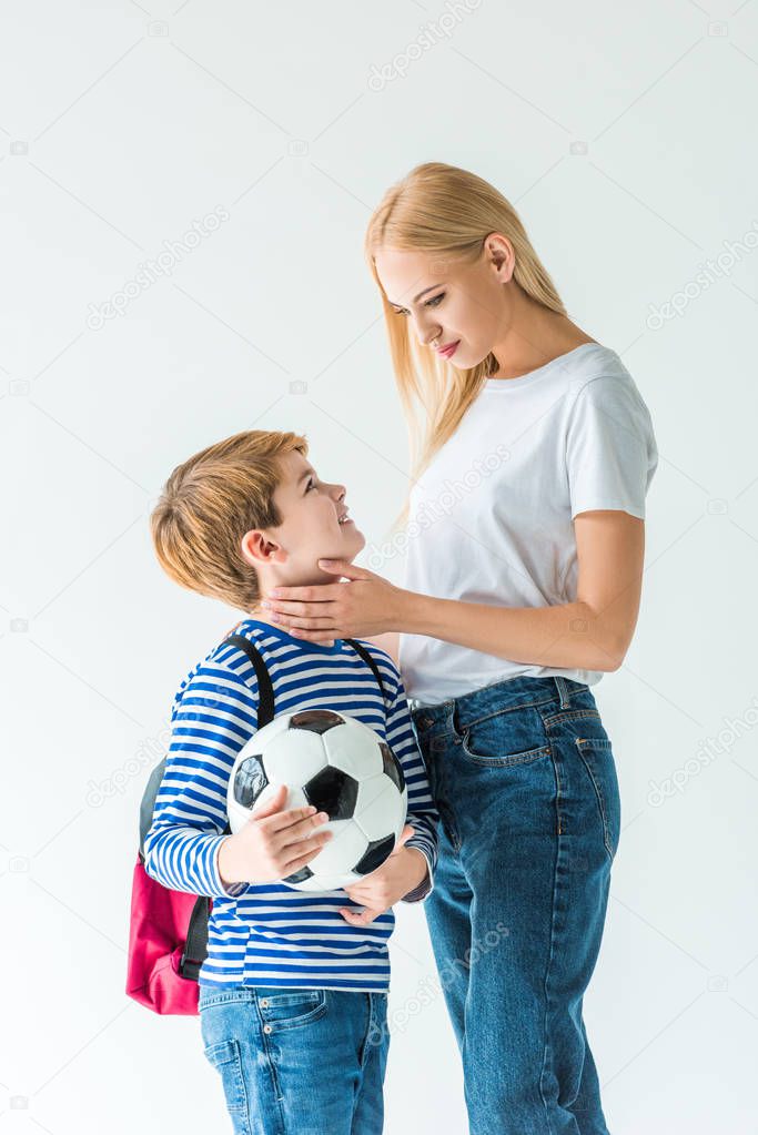 mother palming son, he holding football ball isolated on white