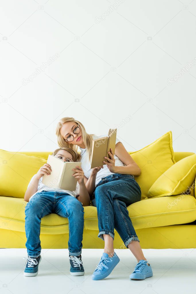 mother and son reading books together on yellow sofa