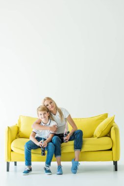 Anne sarılma oğul sarı kanepe ve soda cam şişelerde holding