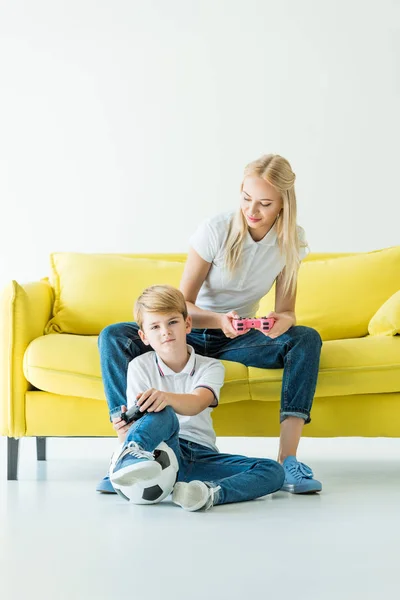 Mãe Olhando Para Filho Enquanto Joga Videogame Sofá Amarelo Branco — Fotografia de Stock Grátis