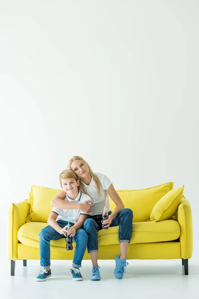 Mother Hugging Son Yellow Sofa Holding Soda Glass Bottles — Free Stock Photo