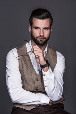Gözlük tutan ve şık yelek gri izole, poz şık adam portresi 