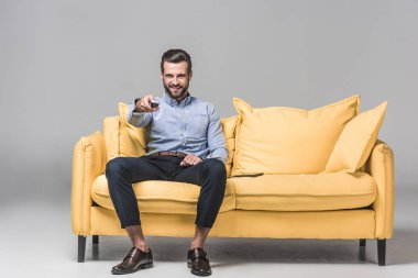 Uzaktan kumanda gri sarı koltukta Tv izlerken ile neşeli işadamı