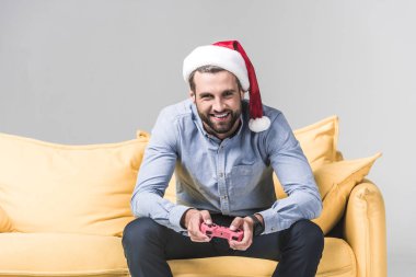 gülümseyen adam gri joystick ile bilgisayar oyunu oynamak santa şapka içinde sakallı