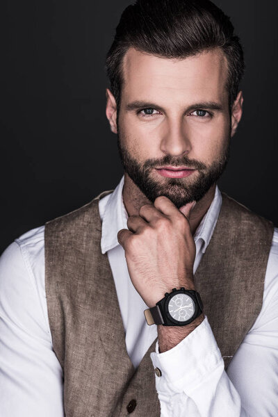 portrait of thoughtful elegant bearded man with wristwatch, isolated on grey