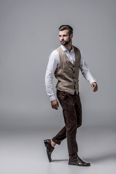 bearded stylish man posing in elegant vest on grey