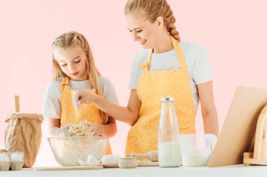 gülümseyen anne ve sarı önlük birlikte pink izole hamur hazırlama sevimli küçük kız