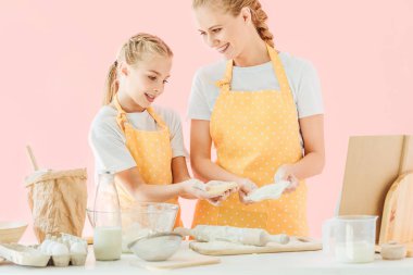 mutlu genç anne ve sevimli küçük kızı birlikte pink izole hamur hazırlama