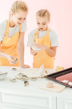 mutlu genç anne ve kızı birlikte pink izole tatil kurabiye hamur hazırlama