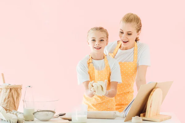 Zaskoczony Młoda Matka Patrząc Córkę Wyrabiania Ciasta Różowym Tle — Darmowe zdjęcie stockowe