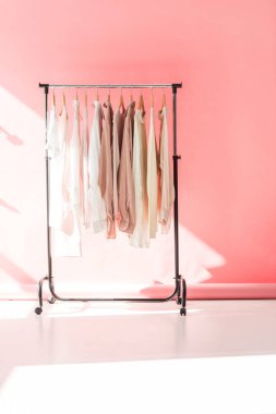 light stylish clothes on hangers in pink boutique