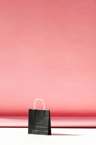 one black shopping bag on pink with copy space