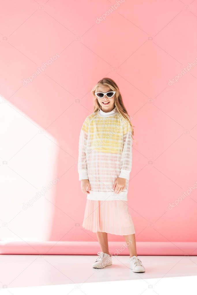 attractive fashionable youngster in sunglasses posing on pink