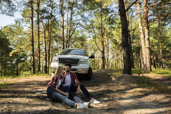 Joven Pareja Sentado Manta Bosque Con Coche Detrás — Foto de stock gratis