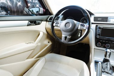 cropped image of black steering wheel and beige leather seats new car on street clipart