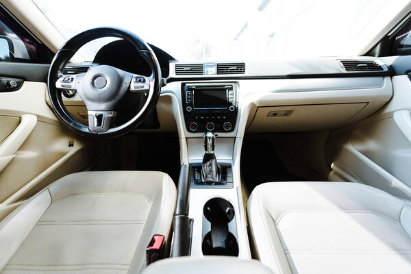 close up of steering wheel and beige leather seats new car on street