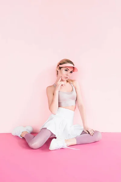 沉思时尚的女运动员在面罩帽子摆在粉红色 — 免费的图库照片