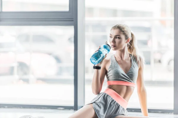运动的年轻女子与智能休息和饮用水在健身房 — 图库照片