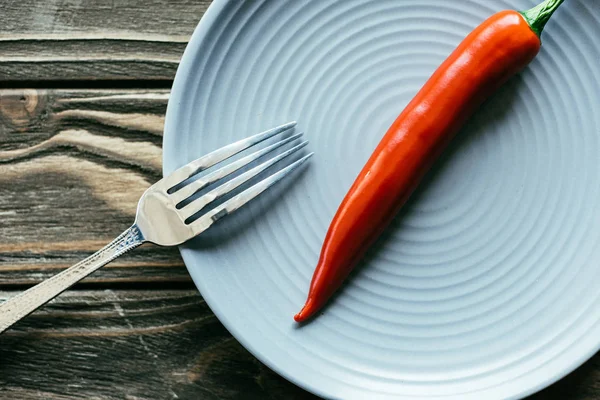 Blue plate with spicy pepper on wooden table — Stock Photo