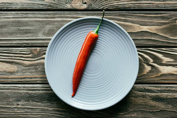 Red hot pepper served on plate on wooden table — Stock Photo