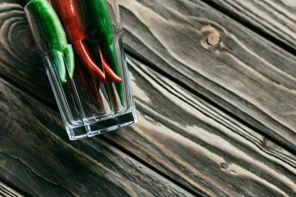 Close-up of glass with hot peppers on wooden table — Stock Photo