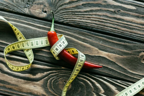 Pimenta vermelha com fita métrica na mesa de madeira — Fotografia de Stock