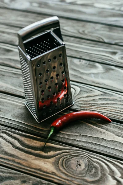 Red chili pepper with metal grater on wooden table — Stock Photo