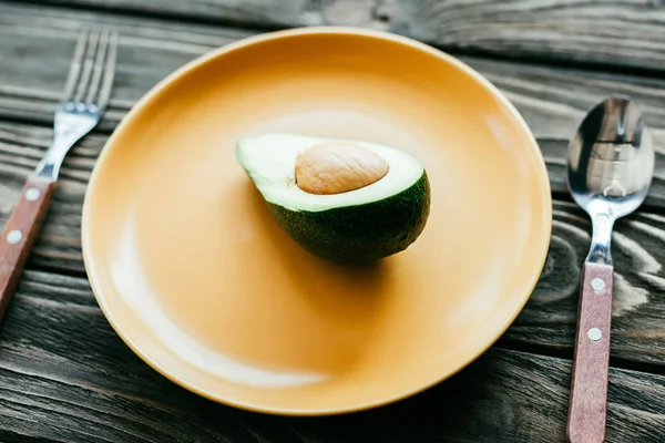 Close-up of cut avocado on plate on wooden table — Stock Photo