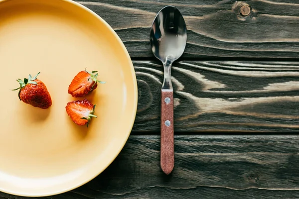Ripe strawberries on plate on wooden table — Stock Photo