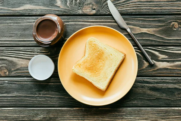 Rebanada de pan tostado y chocolate untado en mesa de madera - foto de stock