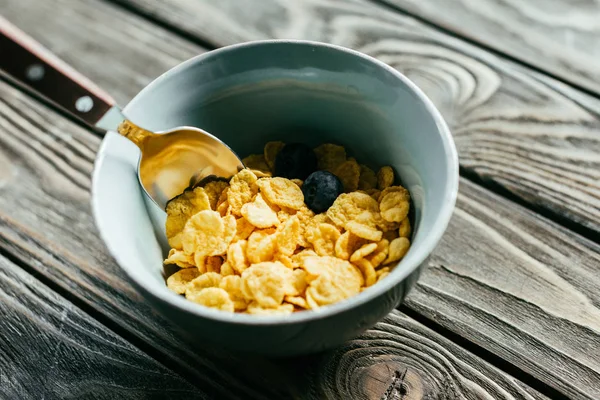 Café da manhã com flocos de milho e mirtilos na mesa de madeira — Fotografia de Stock