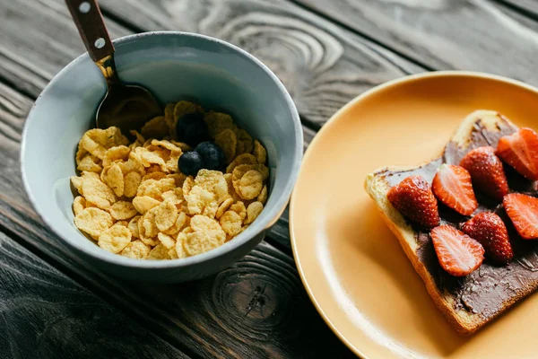 Toast und Flocken mit Beeren auf Holztisch — Stockfoto