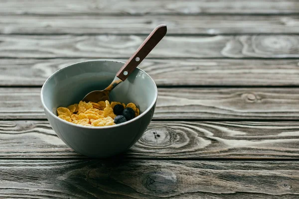 Colazione con corn flakes e mirtilli in ciotola sul tavolo di legno — Foto stock