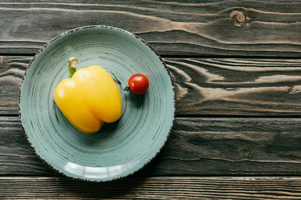 Bell pepper and cherry tomato on plate on wooden table — Stock Photo